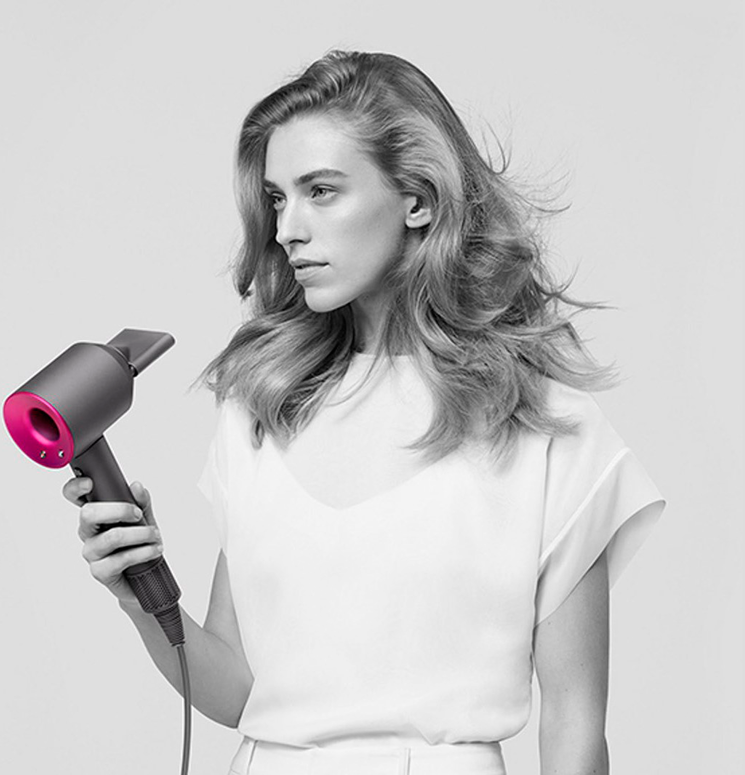 Девушка в черно-белом стиле держит в руке фен Dyson